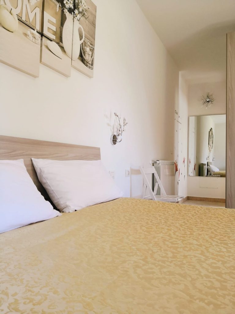 Вертикальный ракурс спального места Home с кроватью, зеркалом и шкафом